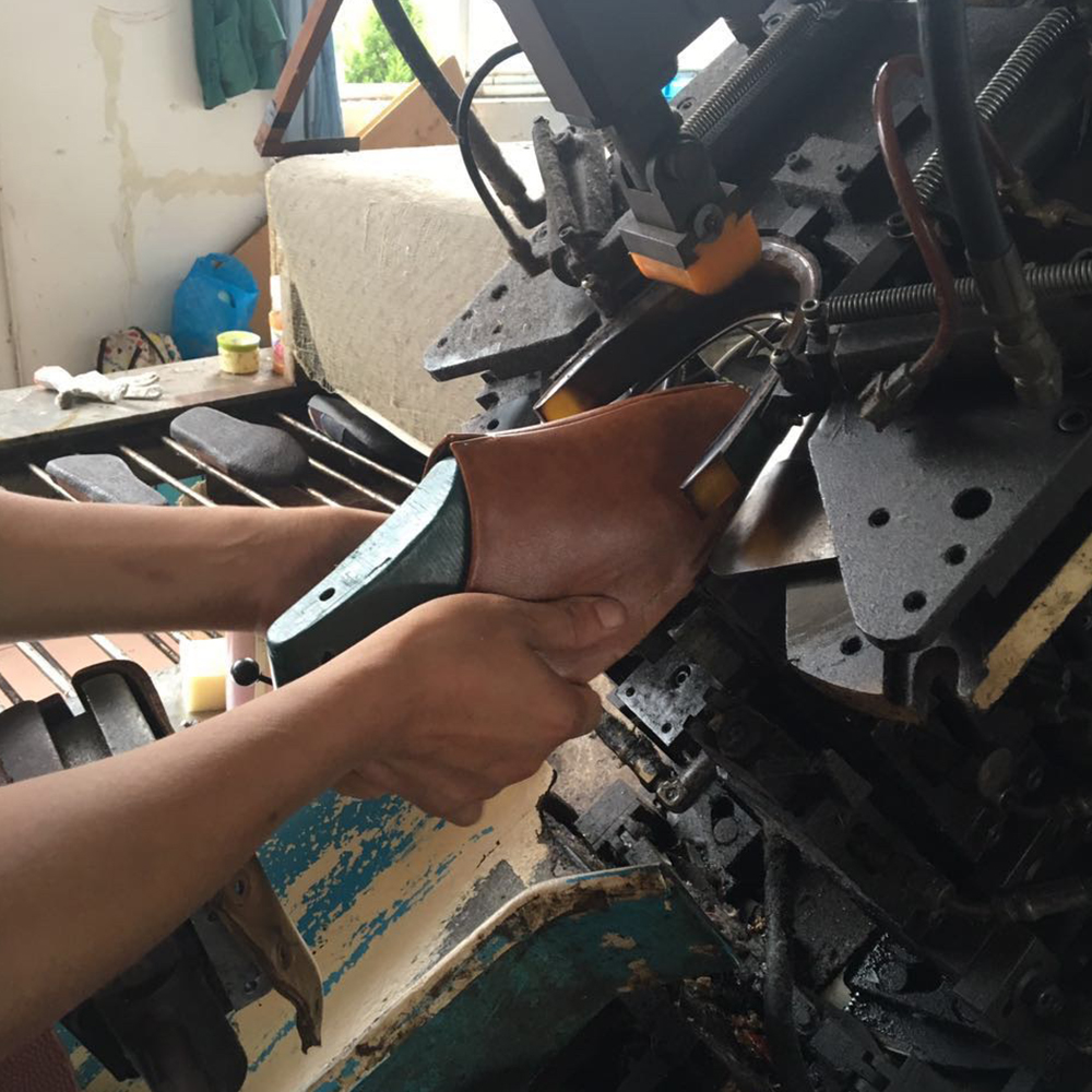 靴の製造と同じように、アッパーとソールを木型を使って手作業で固定しています。
